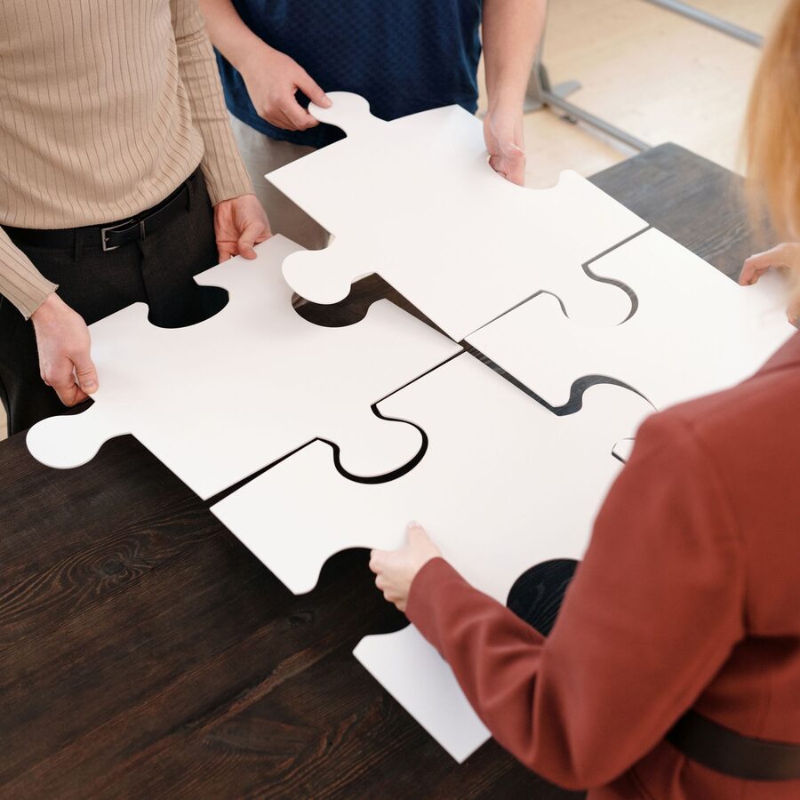 Vier Personen fügen gemeinsam grosse Puzzleteile zusammen