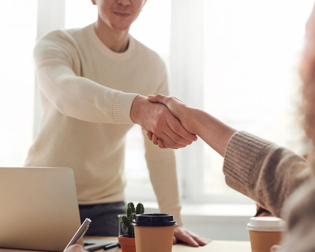 Handschlag über einen hellen Besprechungstisch