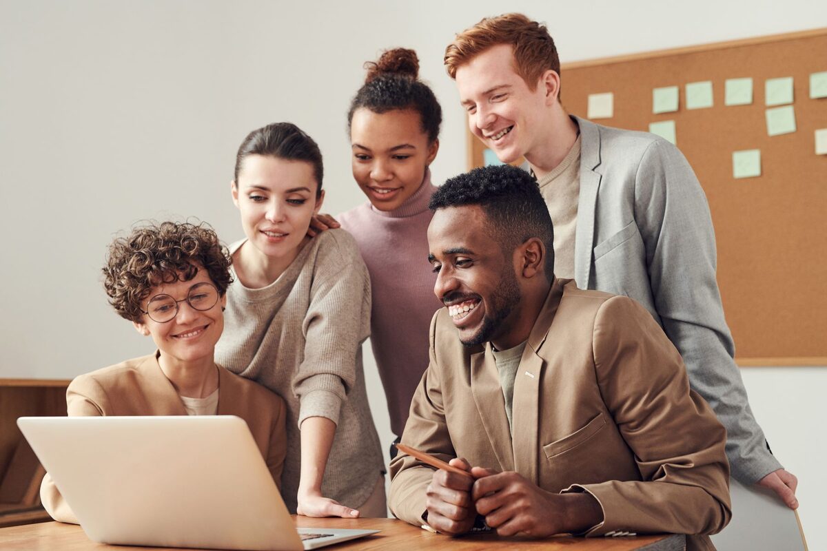 Team schaut gemeinsam lächelnd auf einen Laptop